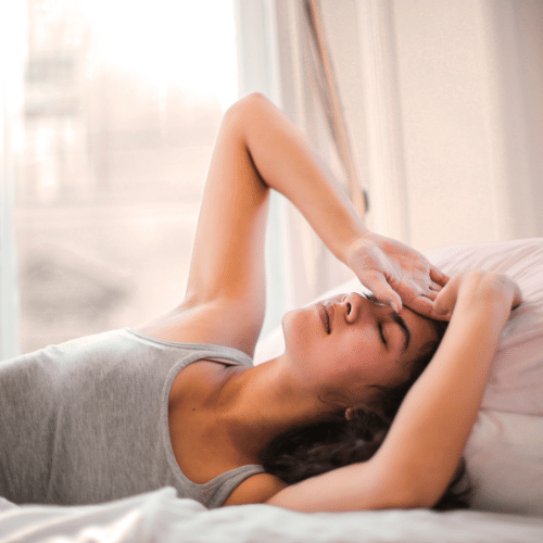 Are candles bad for you?  Woman holding her head in pain on a bed